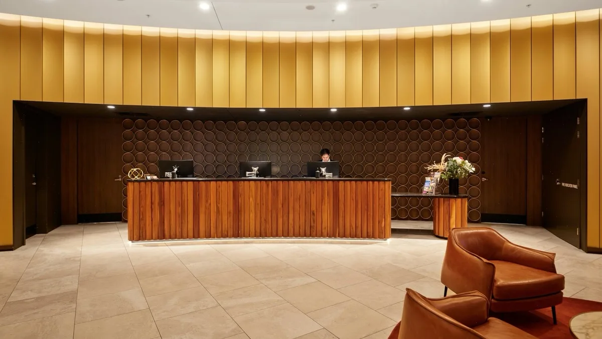 Recepcja hotelowa z drewnianą ladą i monitorami komputerowymi